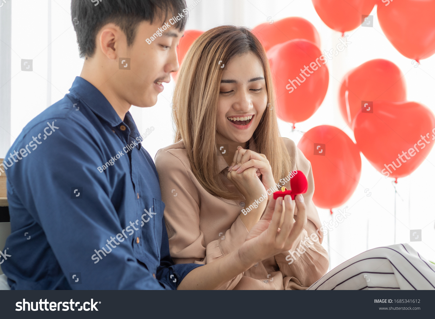 Young and smile face Asian man giving and opening ring box for his lover young and beautiful pretty woman while she very happy and excited face. Concept for love  sharing time and ask for wedding.