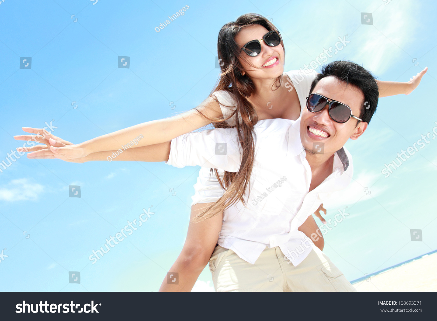 Man carry the girl on his back having fun together on the beach