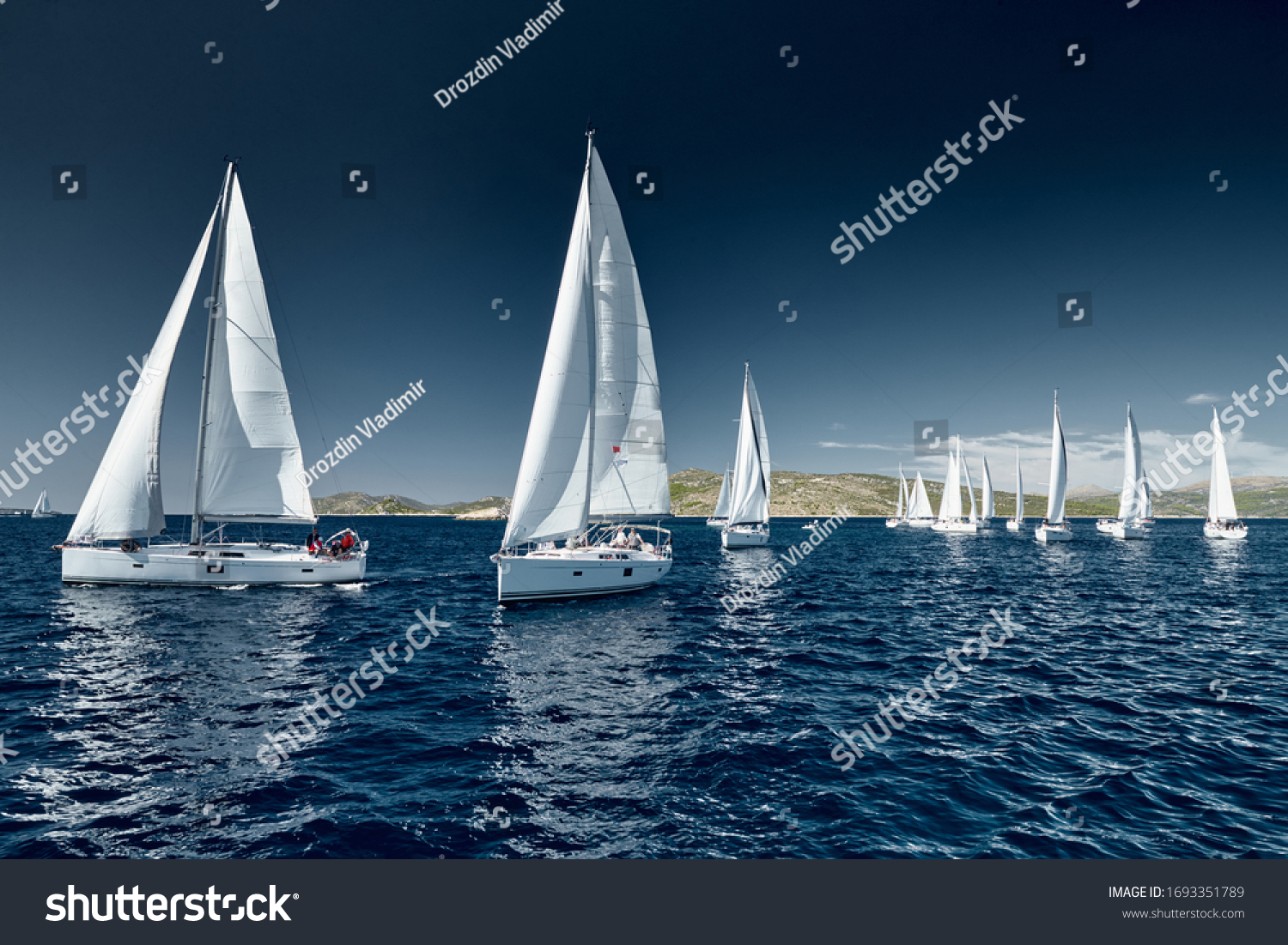 Sailboats compete in a sail regatta at sunset race of sailboats reflection of sails on water multicolored spinnakers number of boat is on aft boats Bright colors