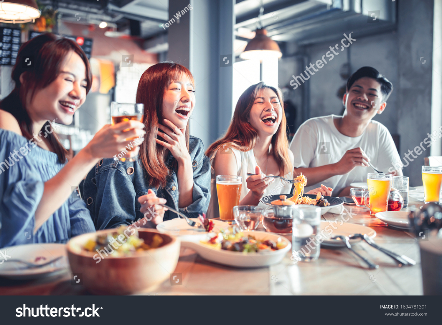 happy young group dining and drinking beer at restaurant