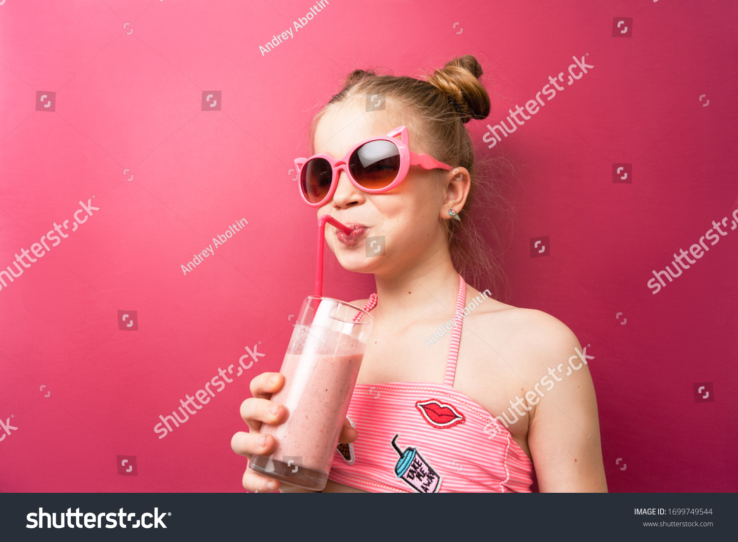 Vibrant colors: A girl in sunglasses in a pink bathing suit drinks a cocktail through a pink straw and exclaims in surprise.
