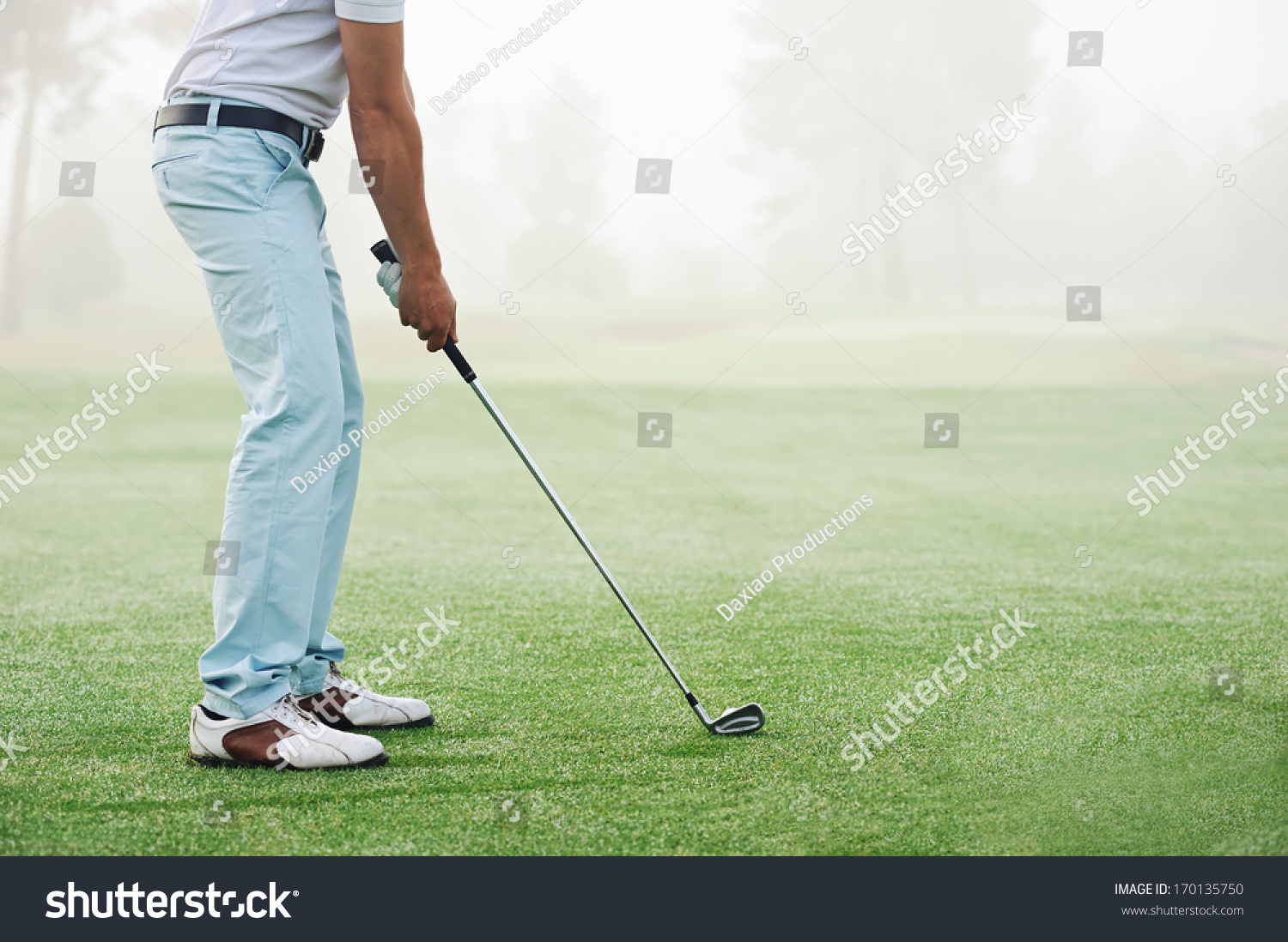 Golfer hitting golf shot with club on course while on summer vacation