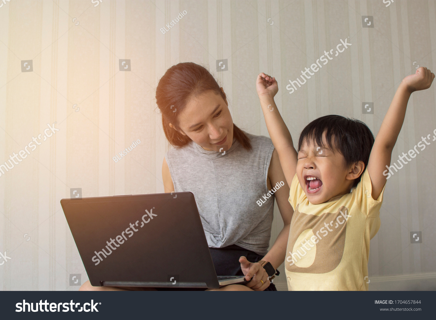 Mom and little son cheering while playing game in laptop Happy family concept.