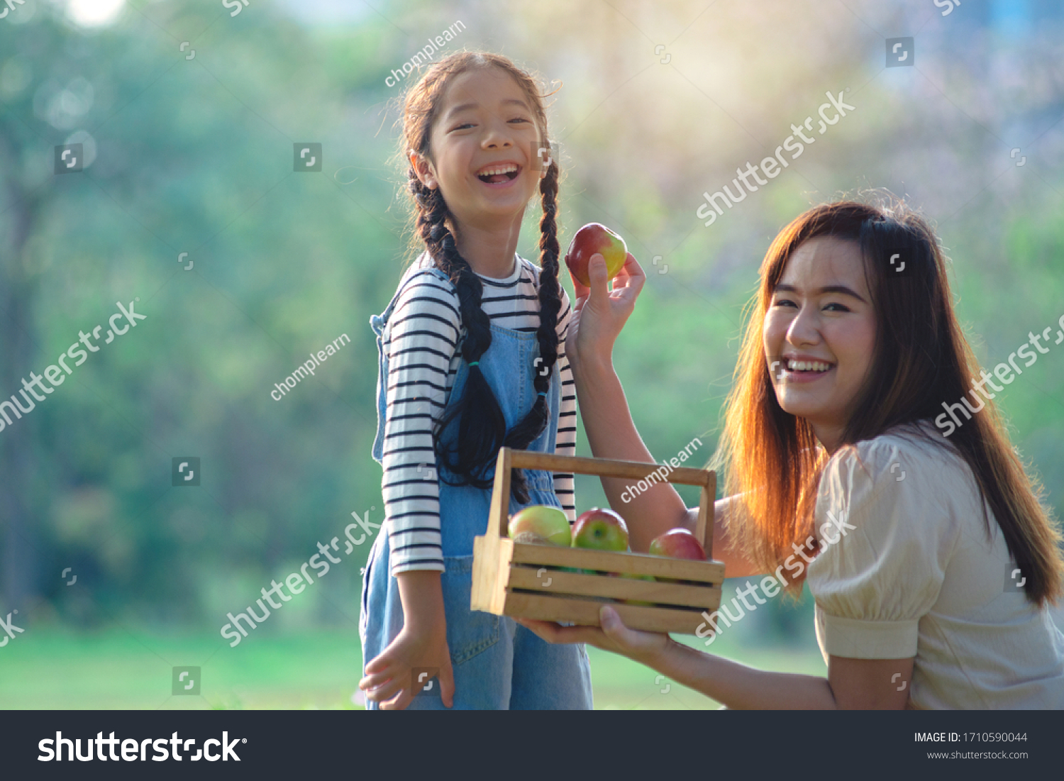 Happy Asian mother and daughter moments with love in summer park  laughing at the camera
