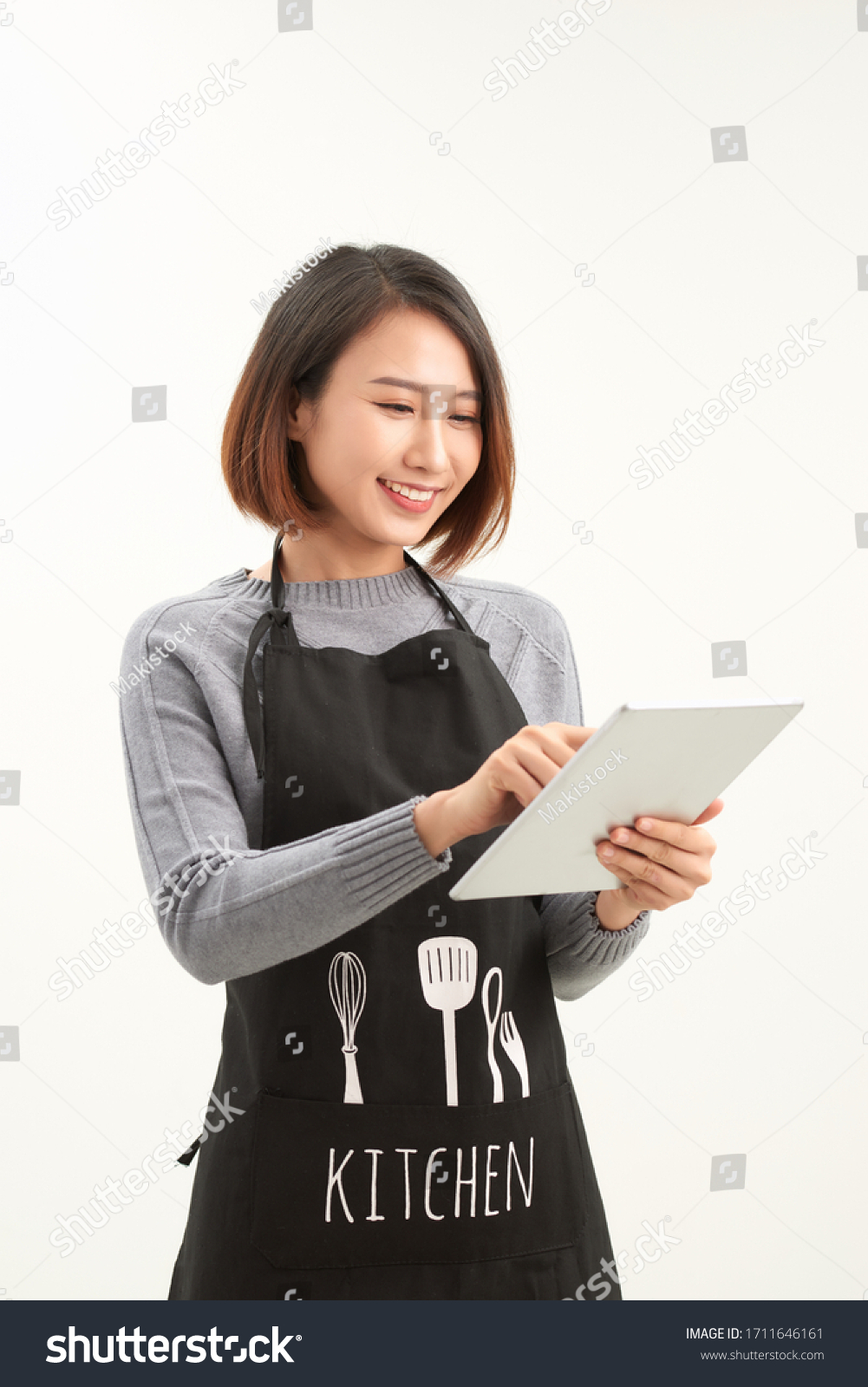 Successful hypermarket employee with black apron holding modern tablet isolated on white background with copyspace