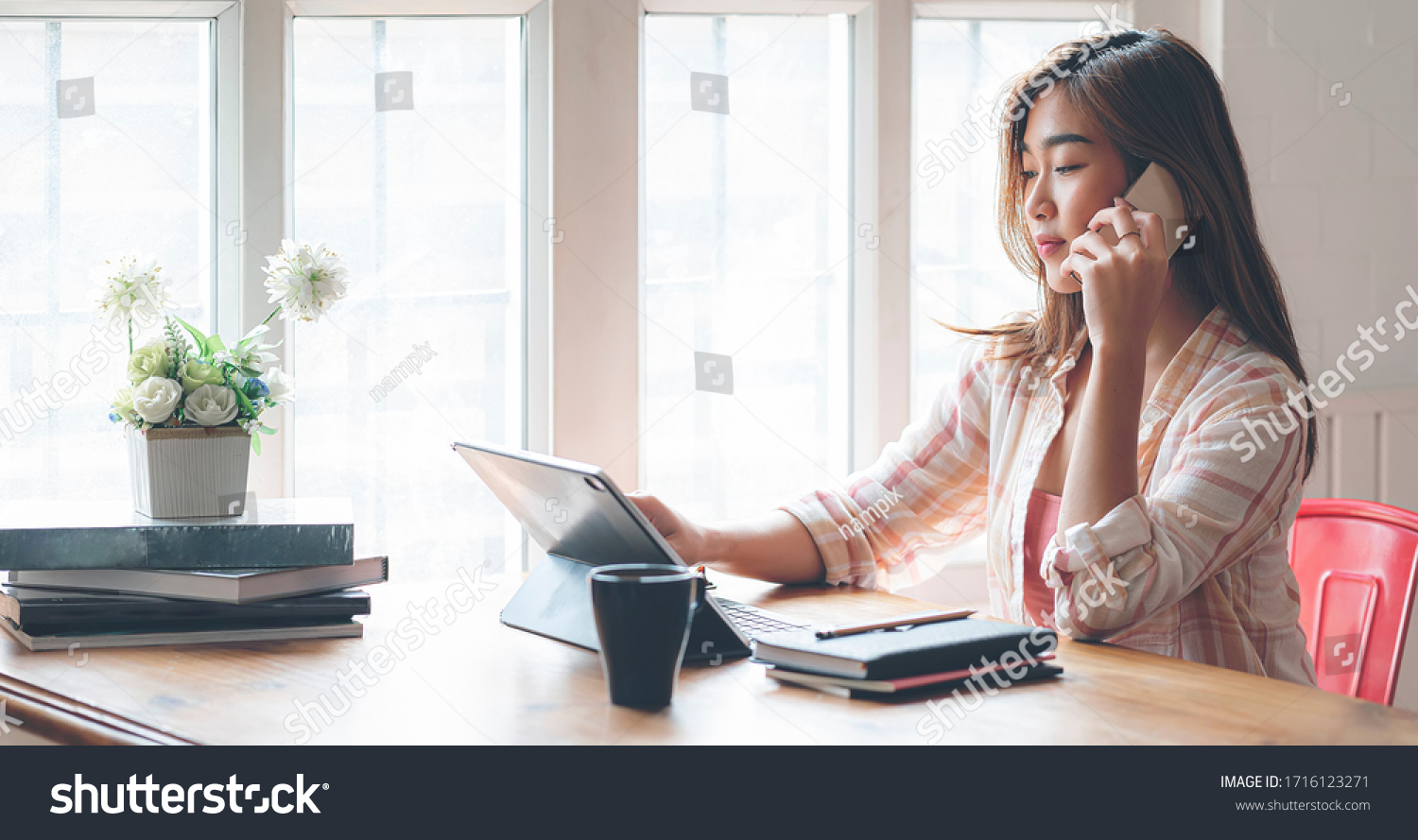 Young beautiful asian woman using smartphone and working with laptop while sitting at office desk  working from home concept.