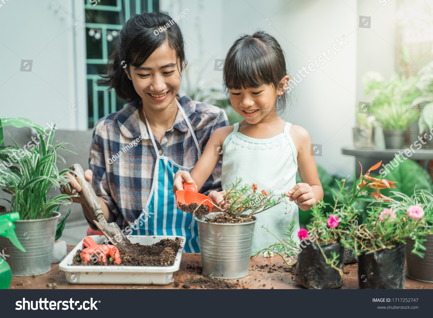 happy excited mother and her daughter gardening together plants some flower at home