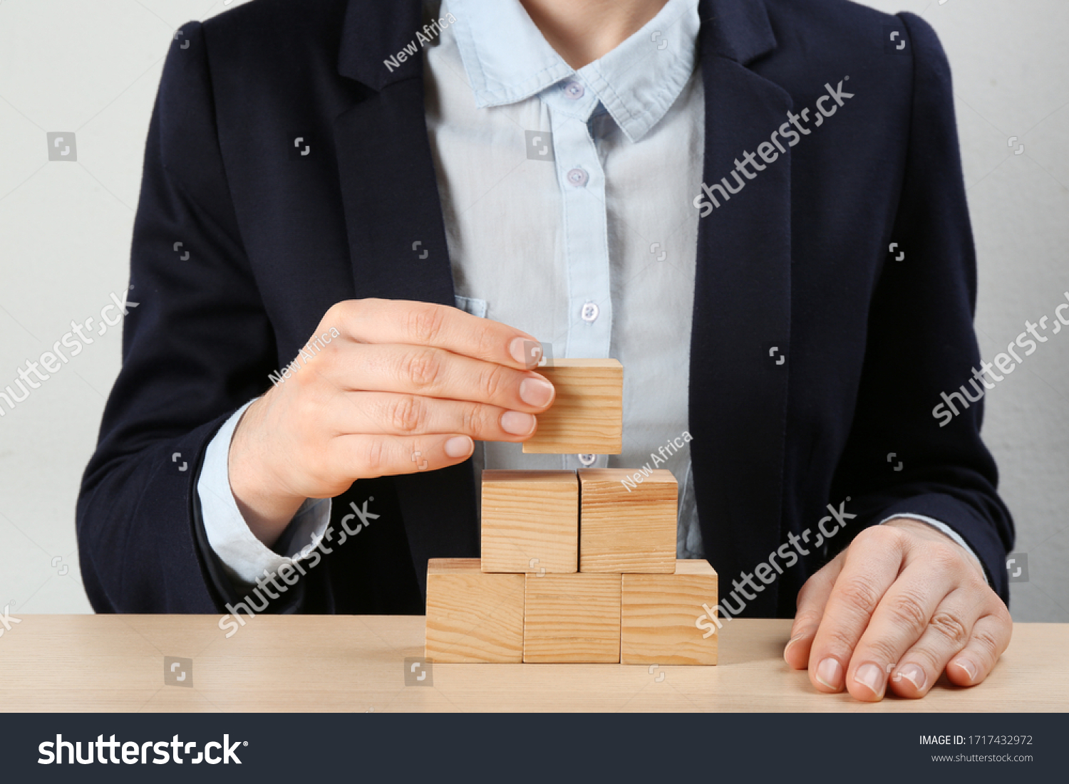 Woman building pyramid at wooden table  closeup. Career promotion concept