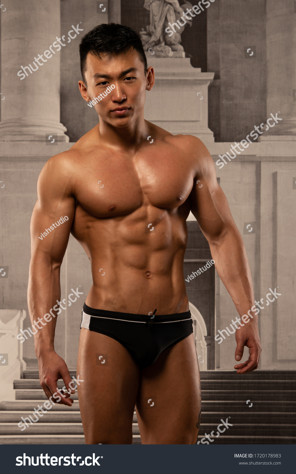 Muscled asian model posing on palace wallpaper background 