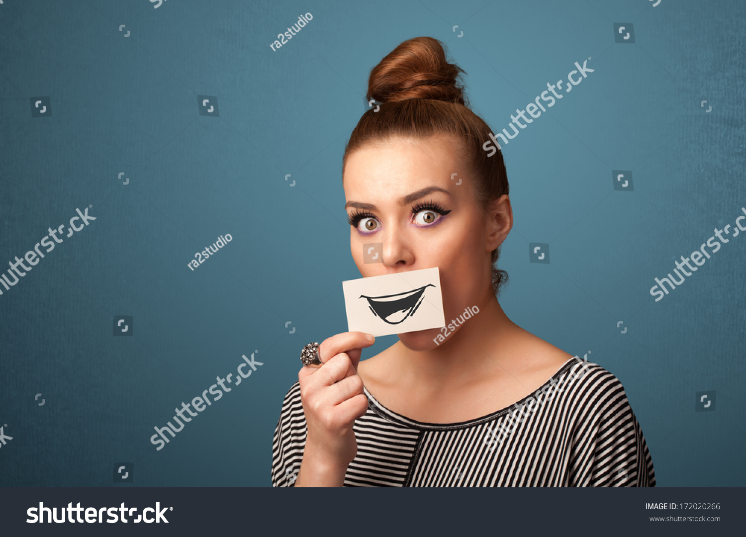 Happy cute girl holding paper with funny smiley drawing on gradient background