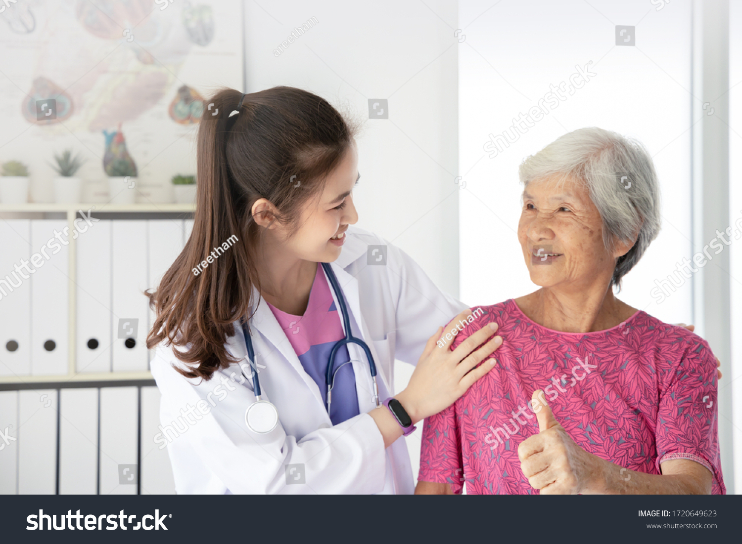 Asian female doctor examine elderly female patient in hospital they feeling happy and smiling patient show thump up sign elderly healthcare promotion concept