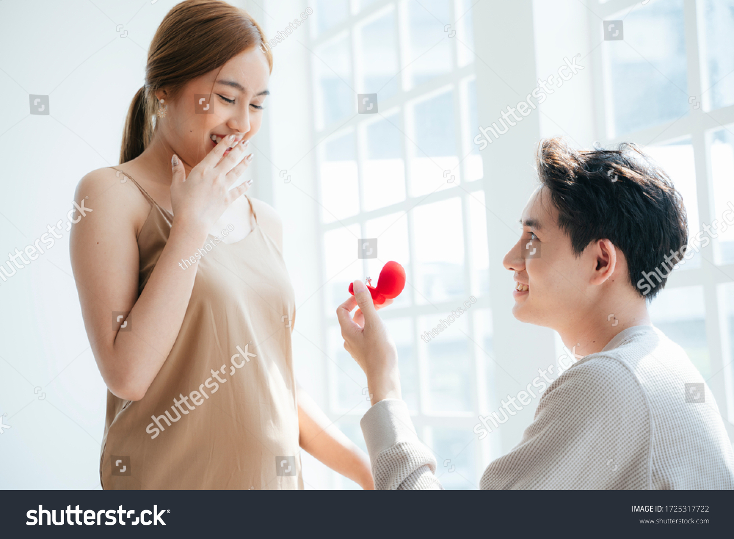 A man give a woman the wedding ring in red box and asking her  will you marry me.