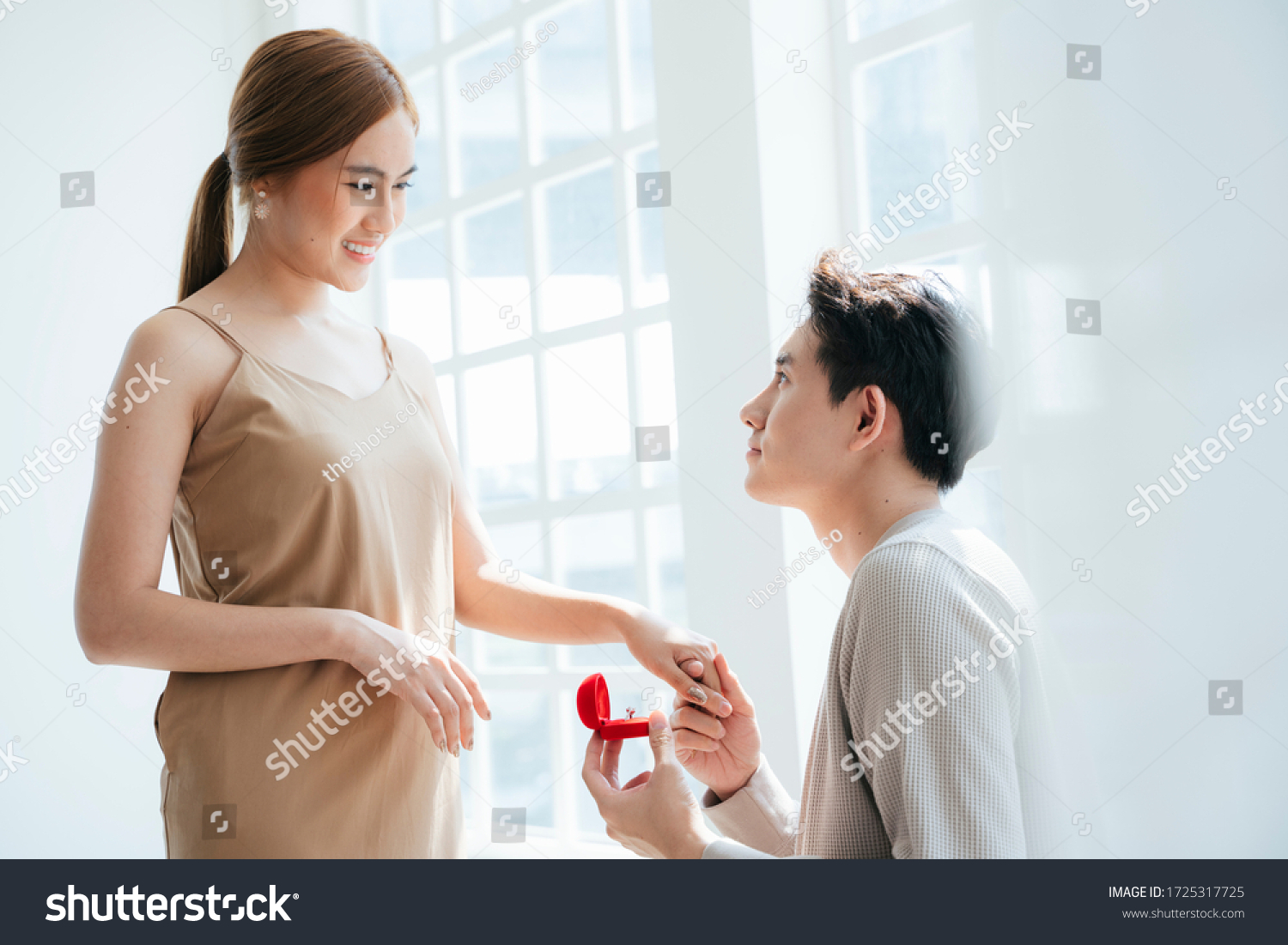 A man give a woman the wedding ring in red box and asking her  will you marry me.