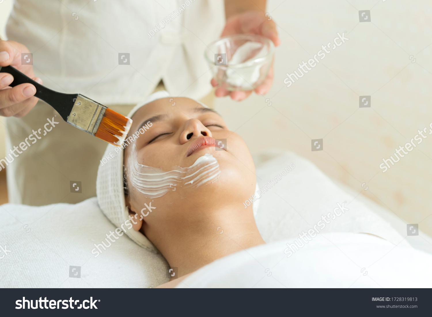 Beautiful young Asian Woman getting facial care by beautician at spa salon  Face peeling mask  spa beauty treatment  skin care concept