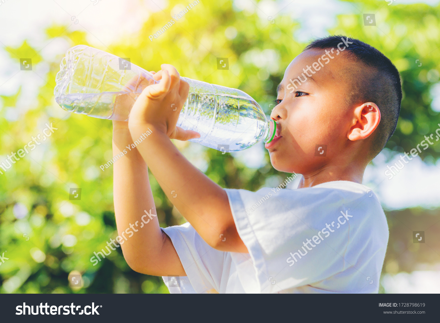 Asian little boy drinking pure water from plastic bottle with nature 