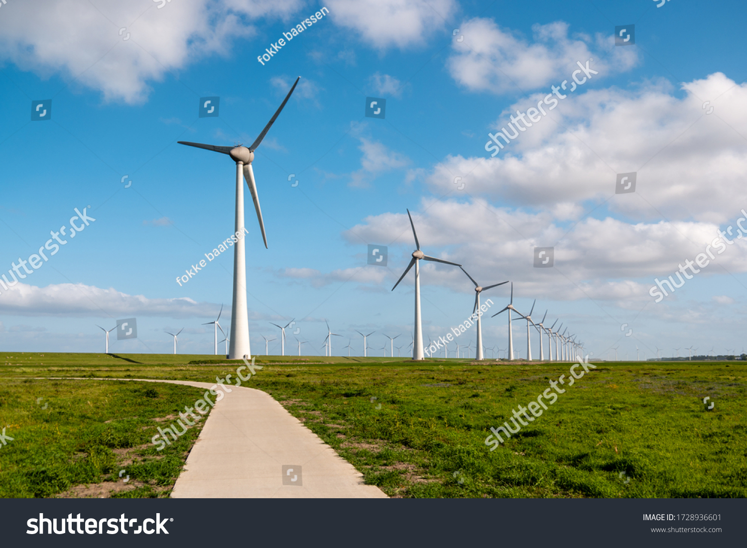 path by the dike to the huge windmill park with huge turbines in the Netherlands Noordoostpolder  green energy wind mill park in Flevoland