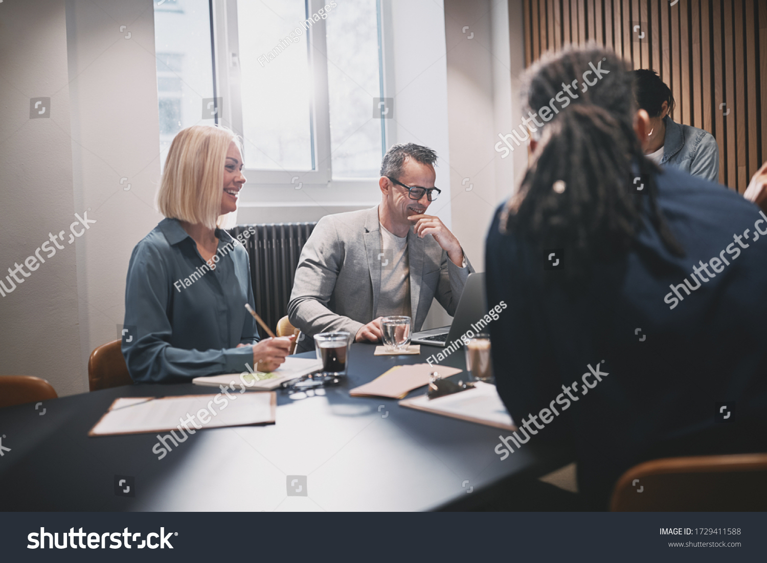Diverse group of smiling businesspeople talking while having a meeting in an office boardroom