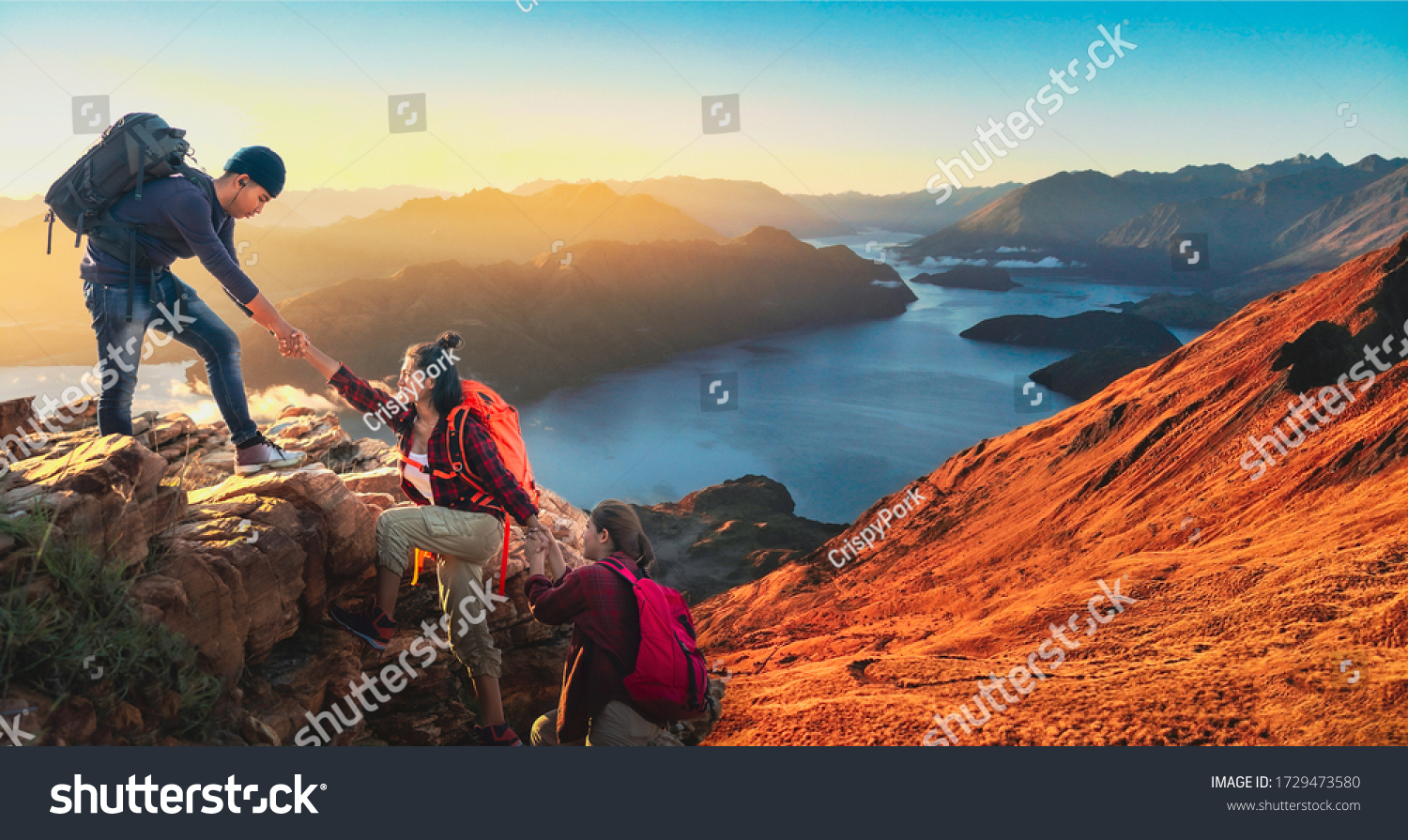 Young asian three hikers climbing up on the peak of mountain. People helping each other hike up a mountain at sunlight. Giving a helping hand. Climbing. Helps and team work concept