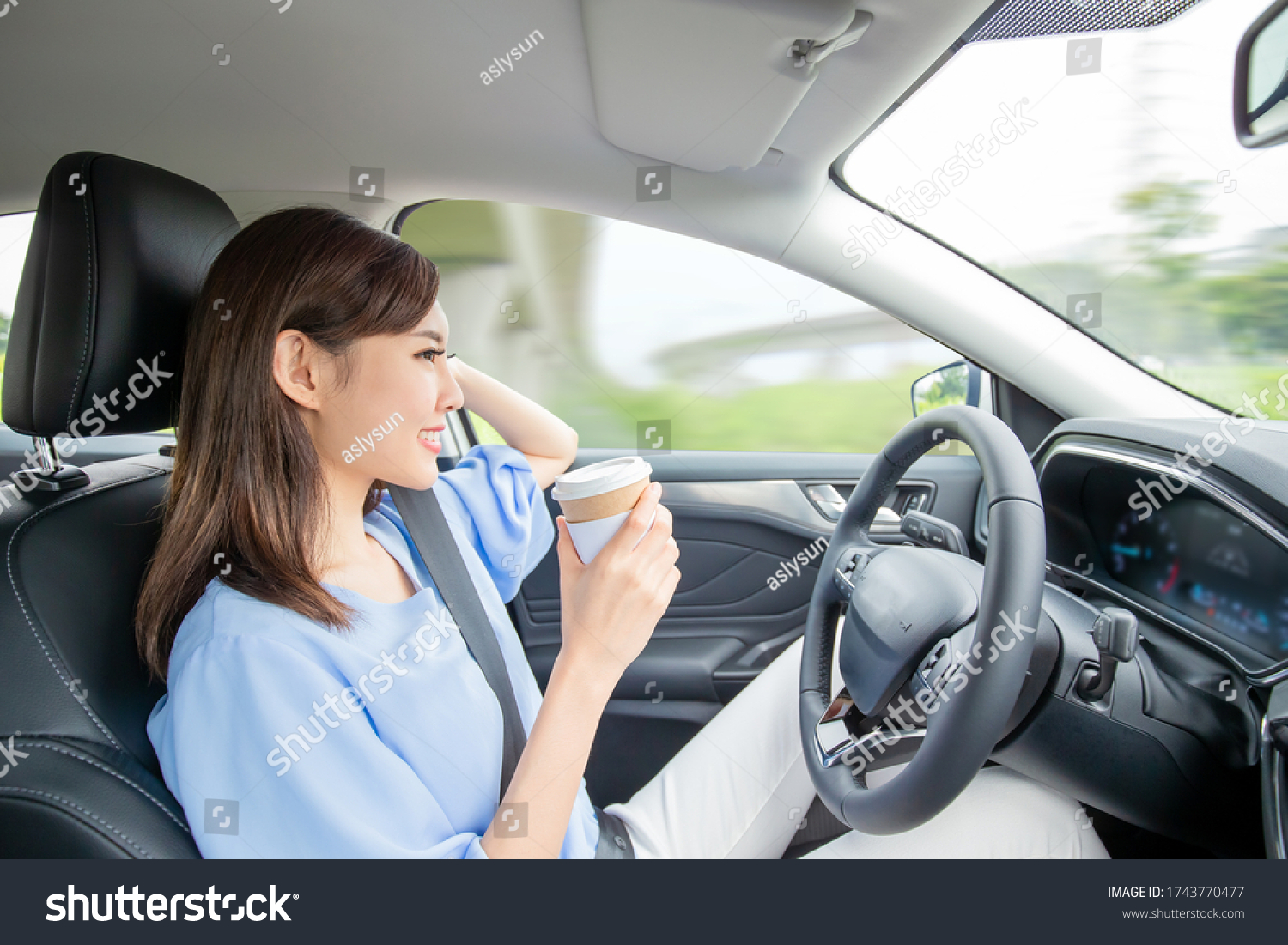 Asian woman in an autonomous self driving car and drink a coffee on the highway