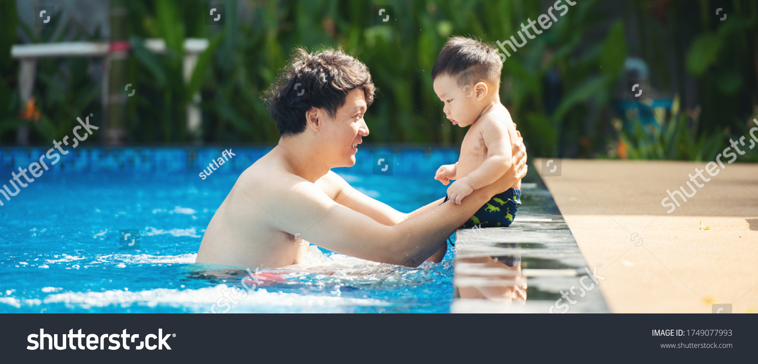 Asian father playing with his little son in pool. Asia people swim in pool outdoor.