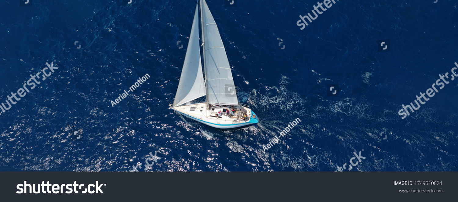 Aerial drone ultra wide photo of beautiful sail boat with white sails sailing open ocean deep blue sea