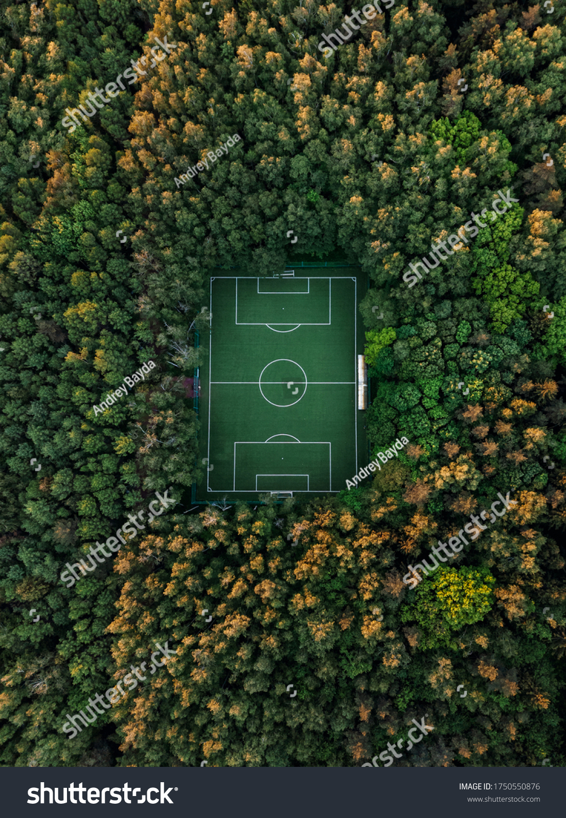 Aerial view of a soccer field in the forest  tall trees around the stadium.