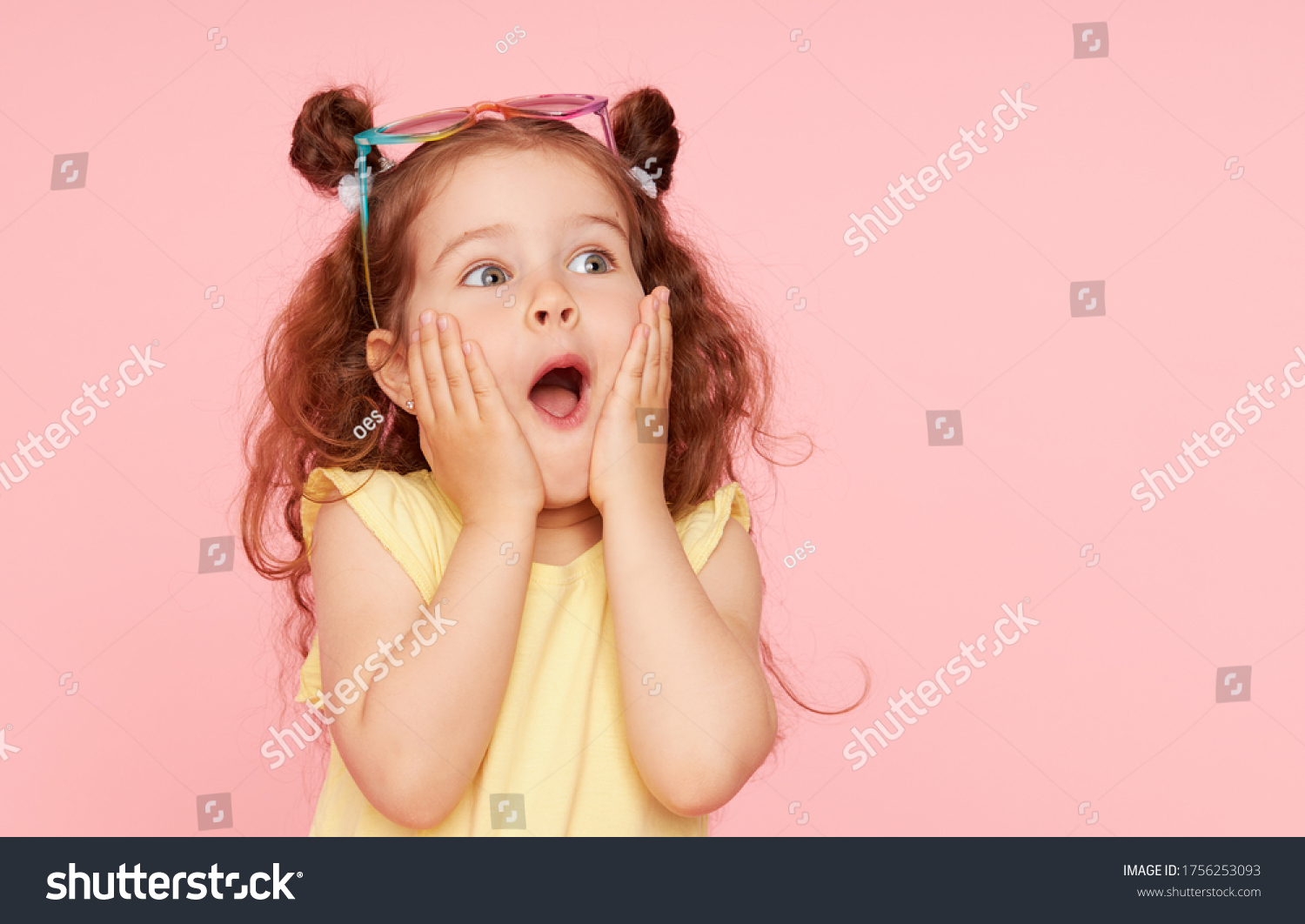 Portrait of surprised cute little toddler girl  in sunglasses over pink background.  Child model have fun and jump. Advertising childrens products