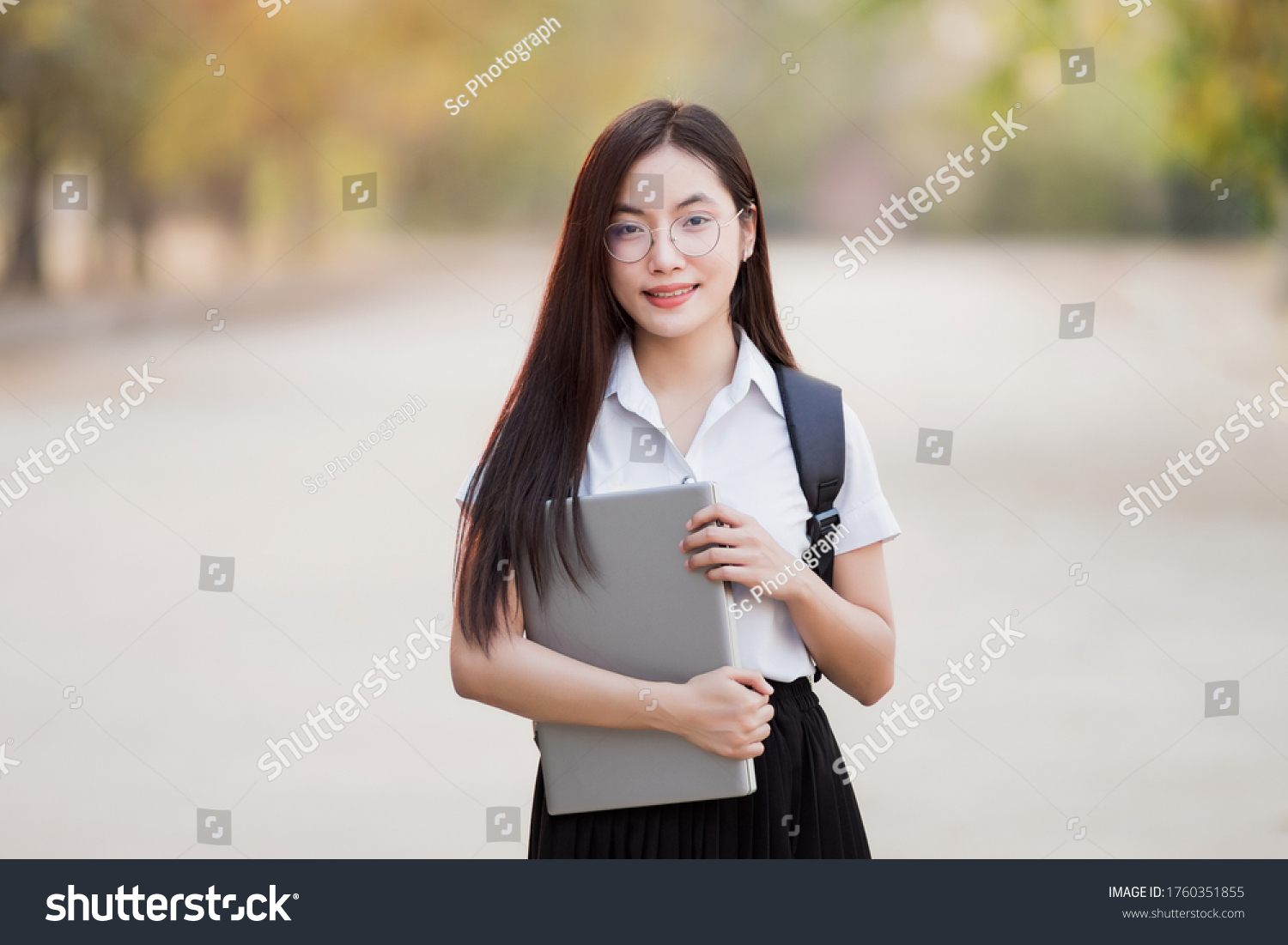 Young teen female Asian university student with bagpack holding laptop in the university campus. Female university student go to university. Back to school concept.