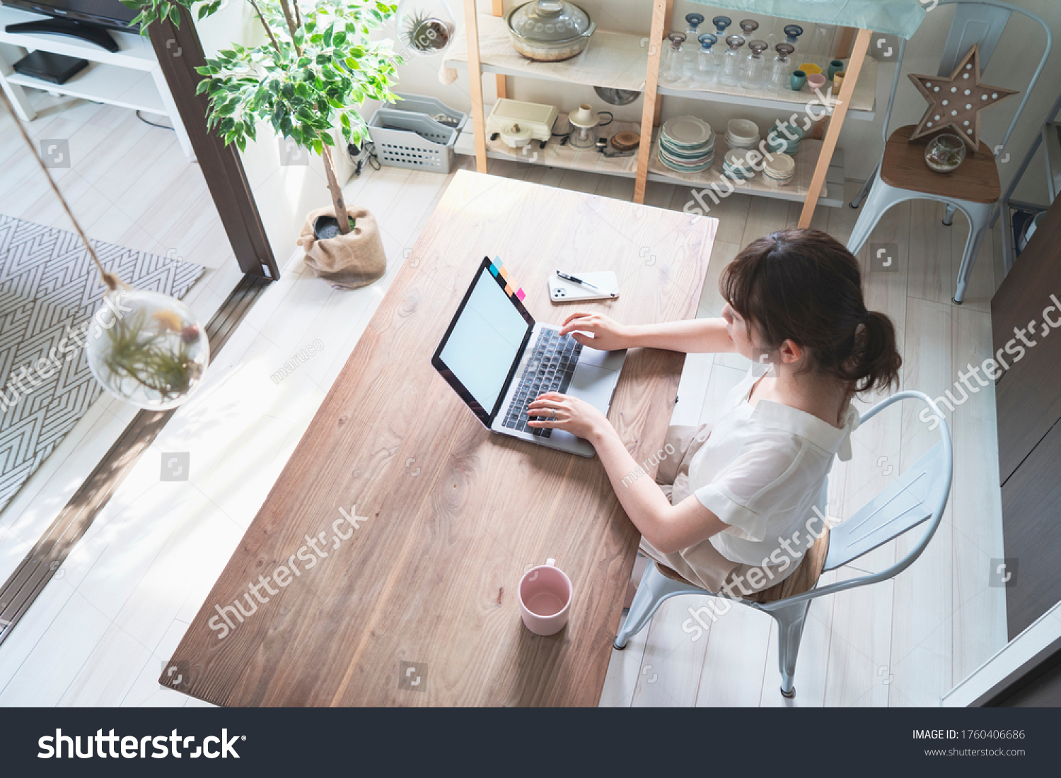 Asian woman doing remote work with laptop at dining table at home