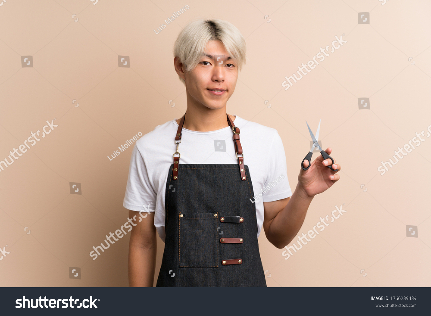 Young asian man over isolated background with hairdresser or barber dress