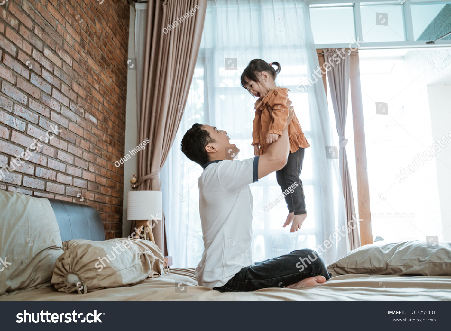 little girl laughed happily when she was lifted up by her father when playing together
