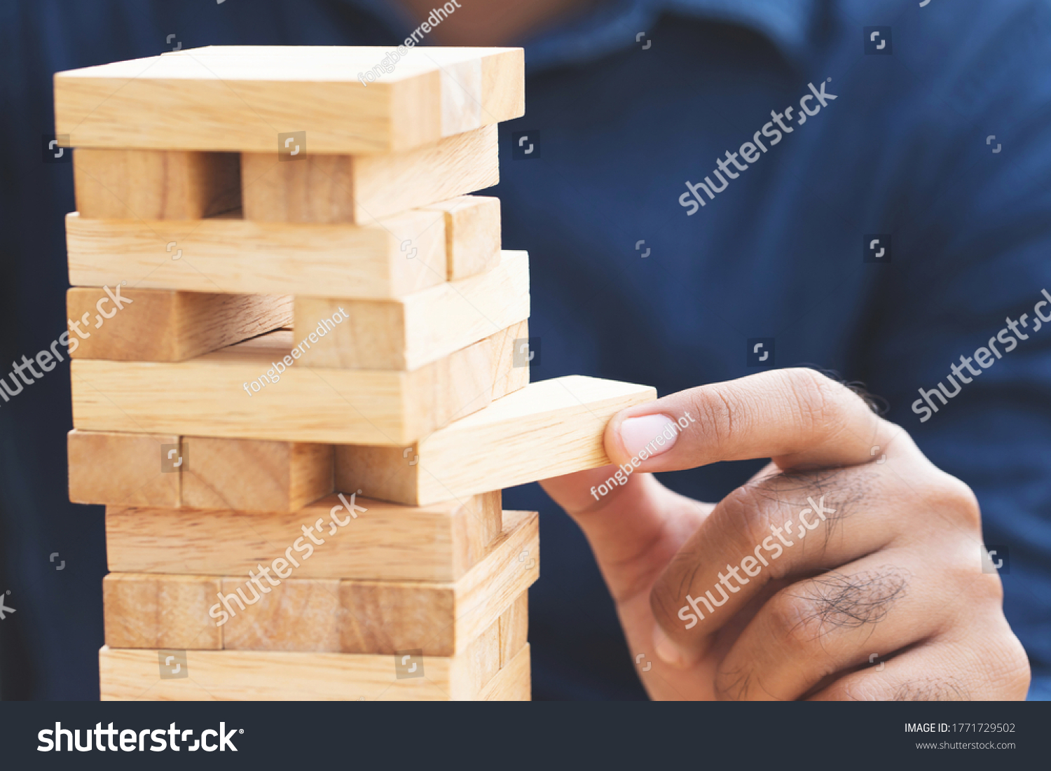 people hand playing take one brown wood block stack game on building tower. concept planning risk and strategy in and engineer construction. 