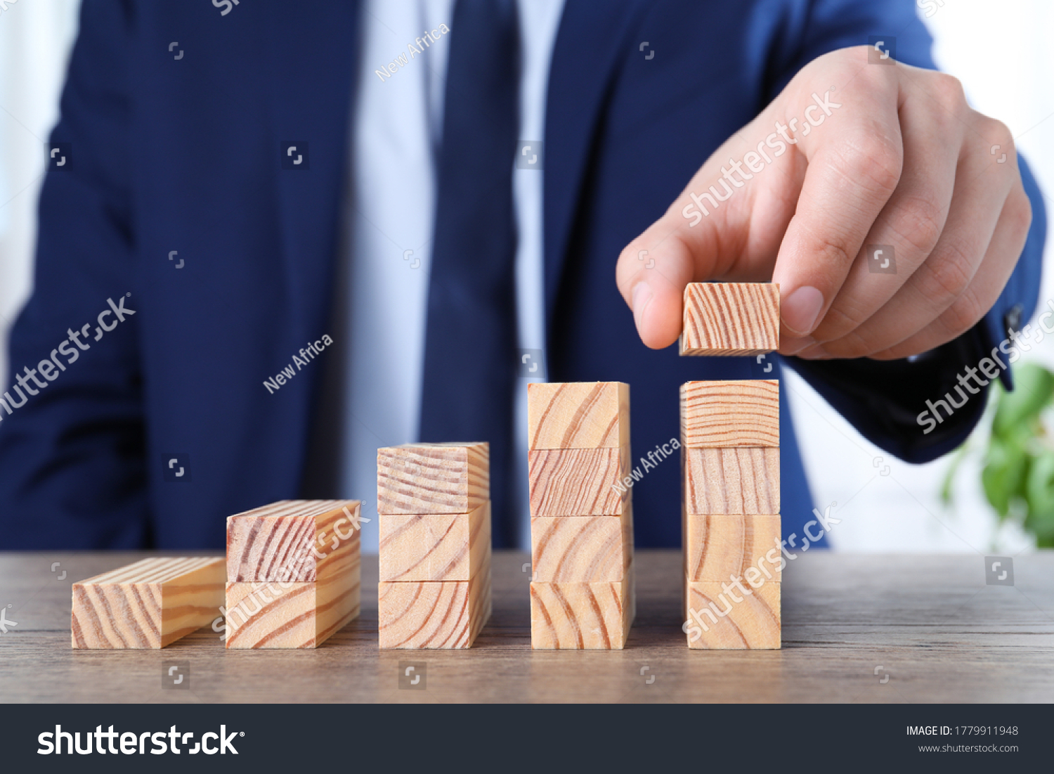 Businessman building steps with wooden blocks on table  closeup. Career ladder