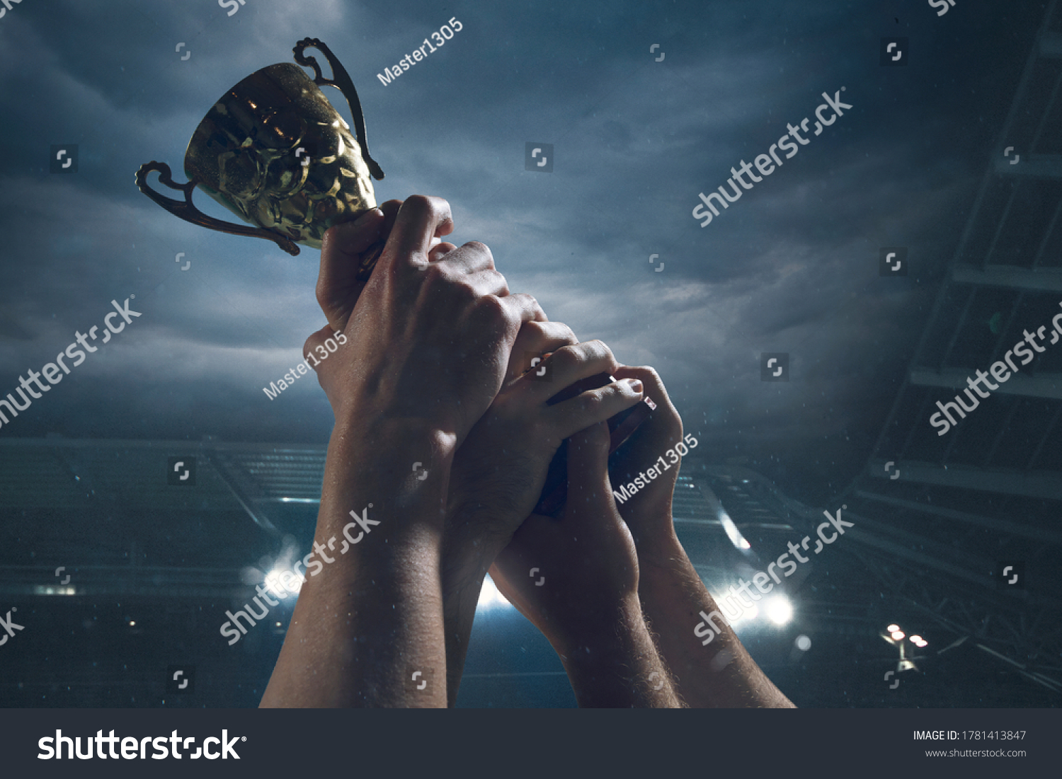 Hard work. Award of victory  male hands tightening the golden cup of winners against cloudy dark sky. Sport  competition  championship  winning  achieving the goal. Prize for success and honor.