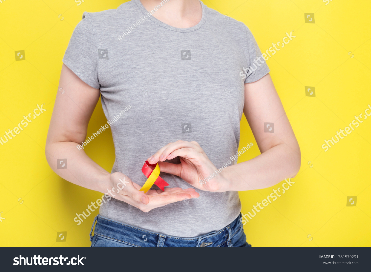 World Hepatitis Day Concept. Girl in gray T-shirt holding red-yellow ribbon area liveras symbol of awareness. Yelow background