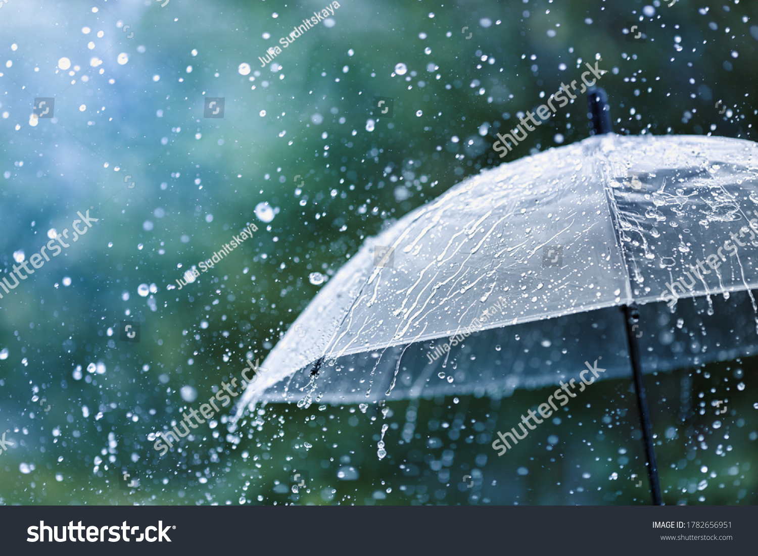 Transparent umbrella under rain against water drops splash background. Rainy weather concept.
