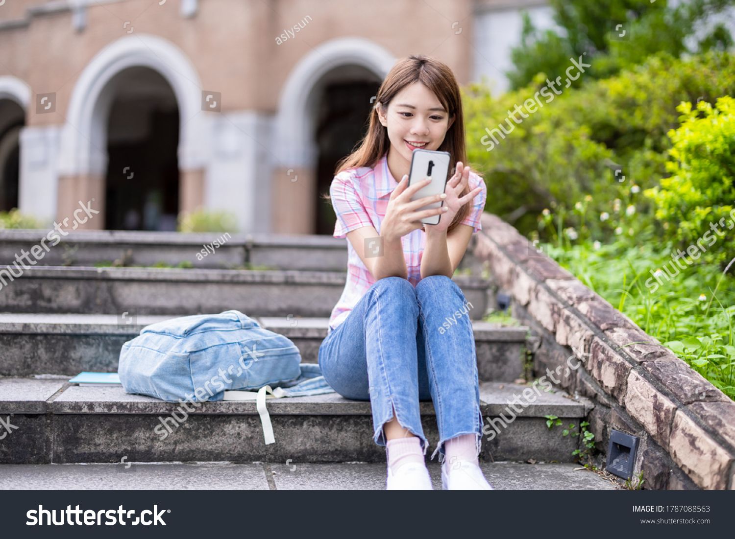 Asian college student use mobile smartphone happily on campus