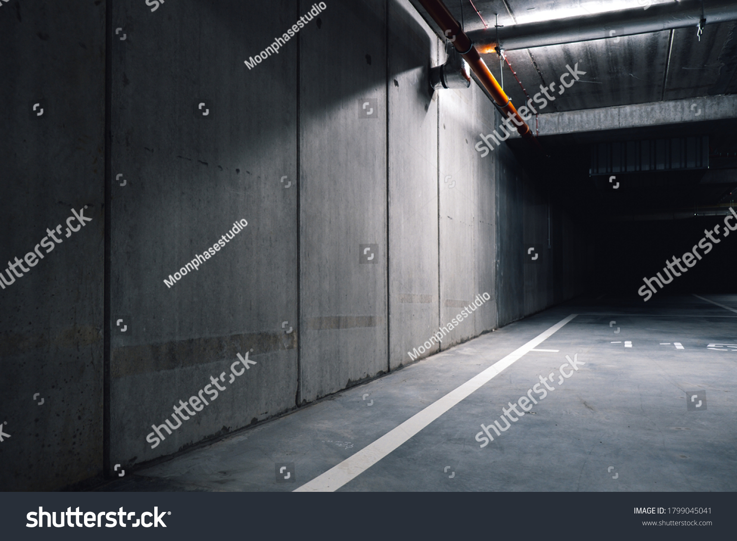 Sci fi looking dark and moody underground parking lot with fluorescent lights on. Long hall