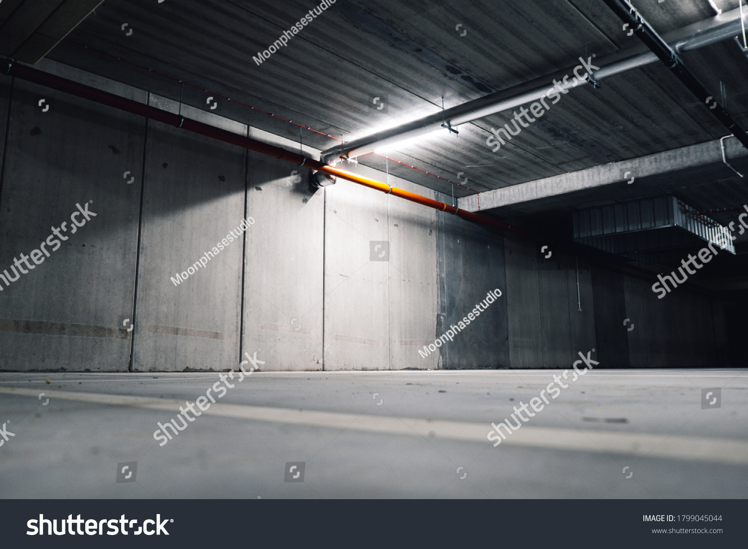 Sci fi looking dark and moody underground parking lot with fluorescent lights on. Long hall