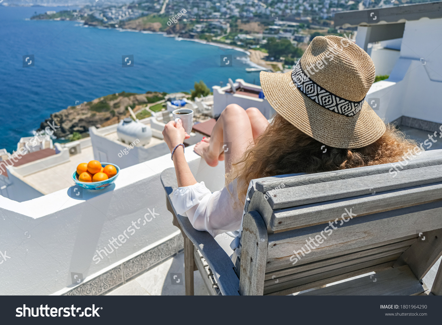 Beautiful young woman straw hat and coffee cup sitting on white terrace balcony of house or hotel with Sea View