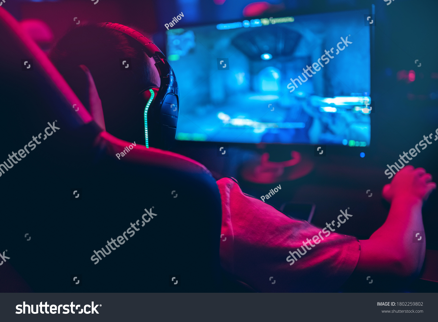 Professional gamer playing online games tournaments pc computer with headphones Blurred red and blue background.