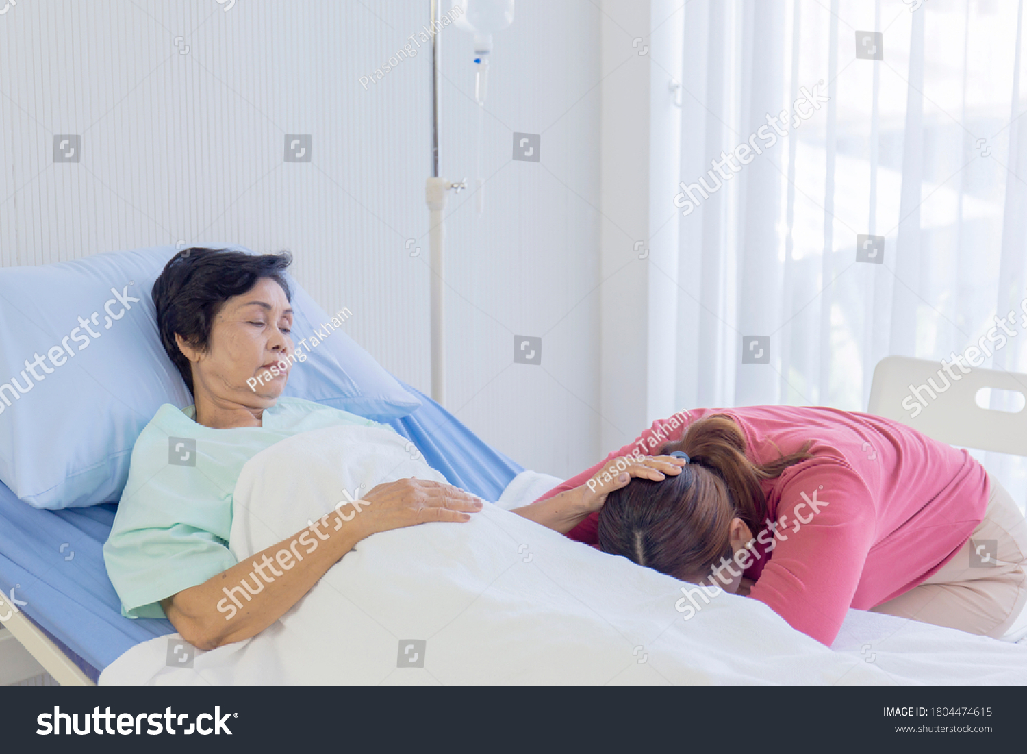 A sick mother in bed  Asian woman rubbed her daughter's head asleep in the hospital bed