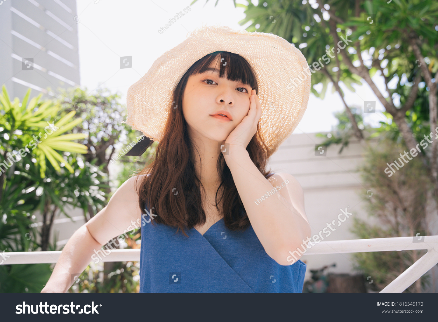 Portrait of young asian woman traveler wearing blue dress and hat outdoors in city.