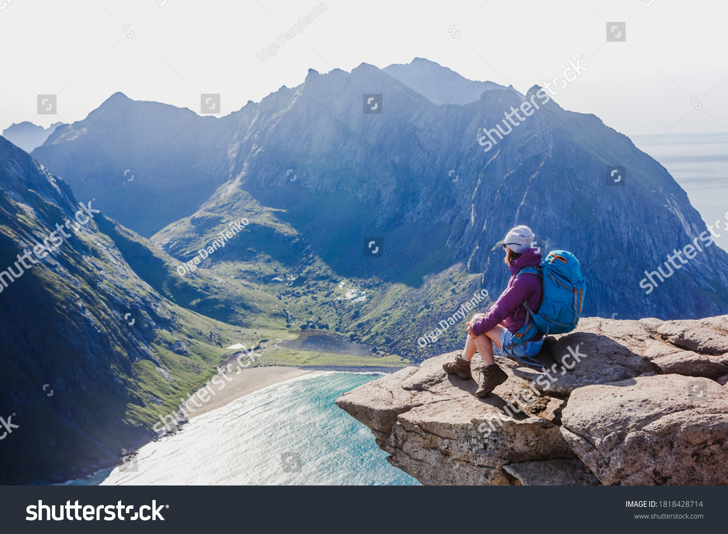 Woman hiker enjoying at the top of the mountain and looking at incredible views of a Norwegian fjord Lofotens. Travel adventure healthy lifestyle concept