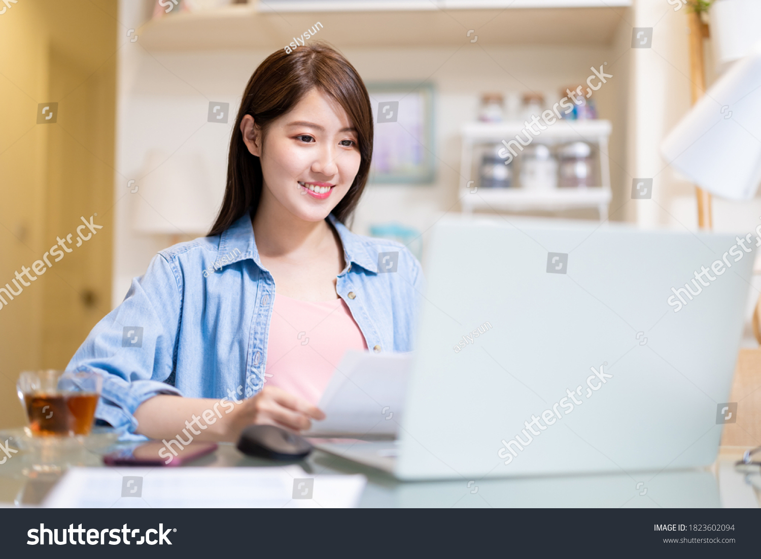 Asian business woman uses laptop computer and smart phone to work at home 