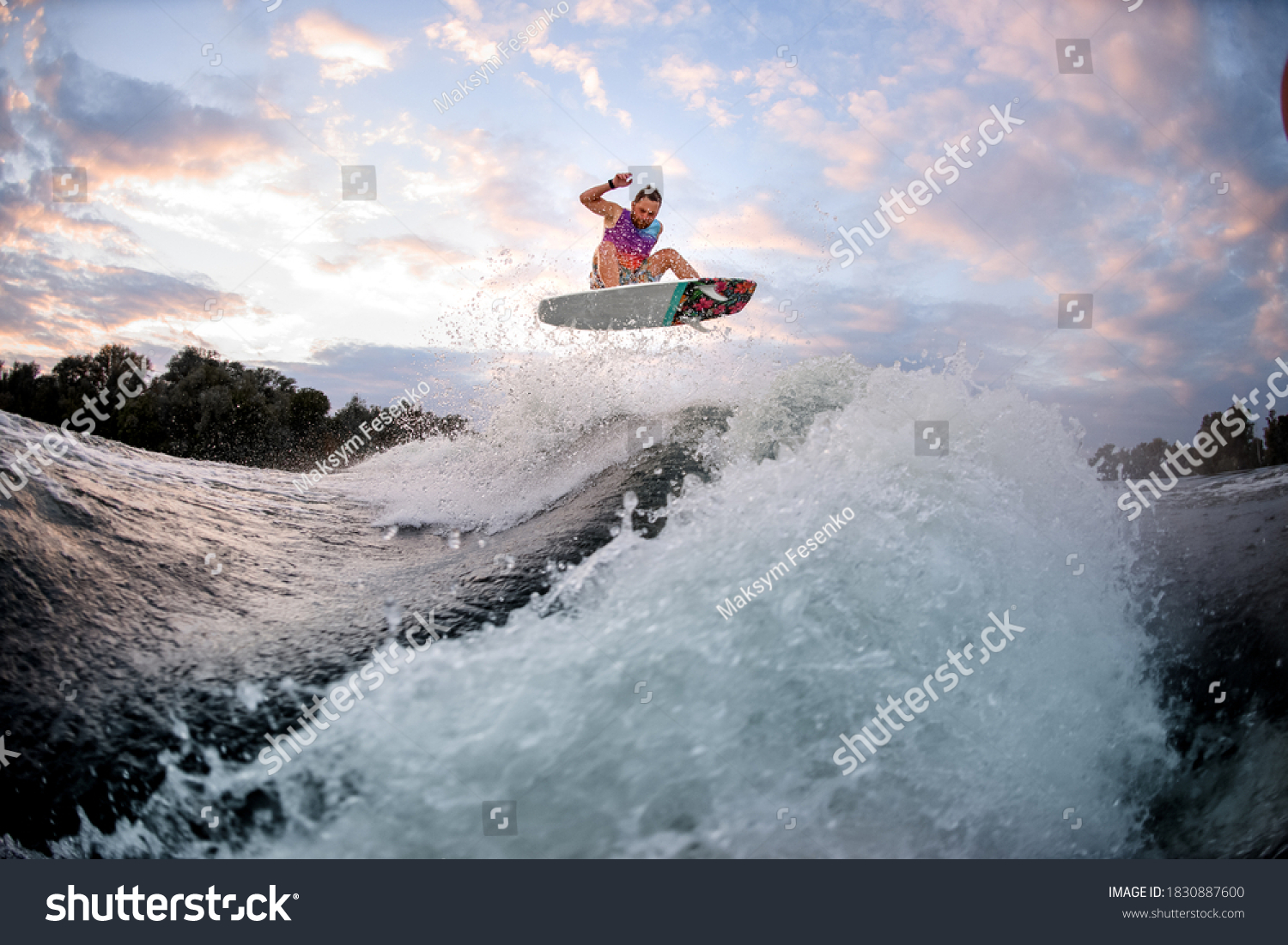 Active man engaged in extreme water sports and jumps high above the wave on the surf style wakeboard.