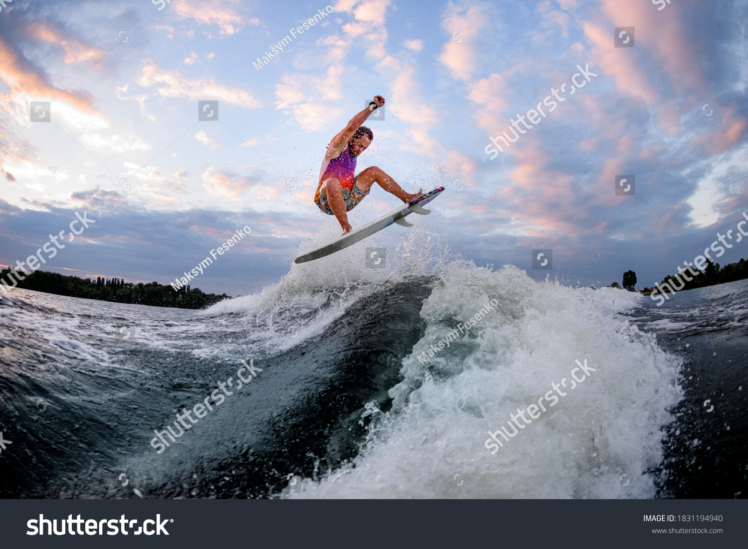 athletic man in bright clothes actively riding large wave doing jumps and tricks on the surf style wakeboard