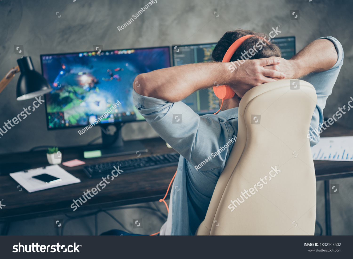 Rear back behind view of his he nice focused guy geek playing web network game remote freelance resting sitting in chair at modern industrial interior loft concrete wall style work place station