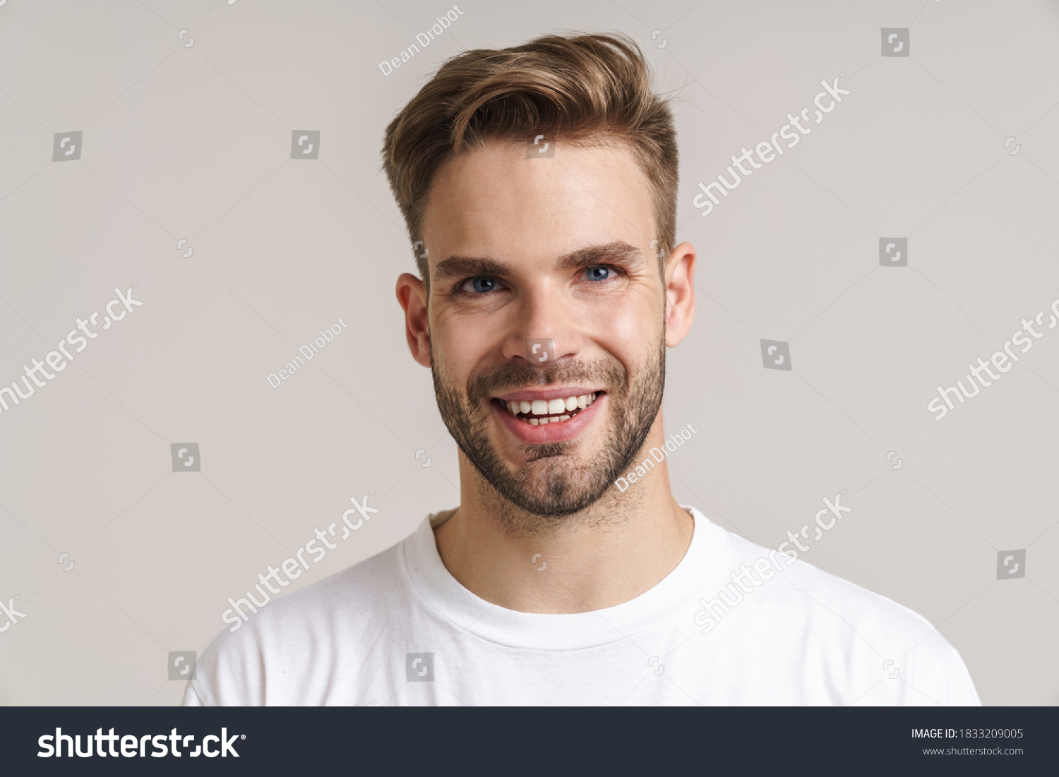 Joyful handsome guy smiling and looking at camera isolated over grey background