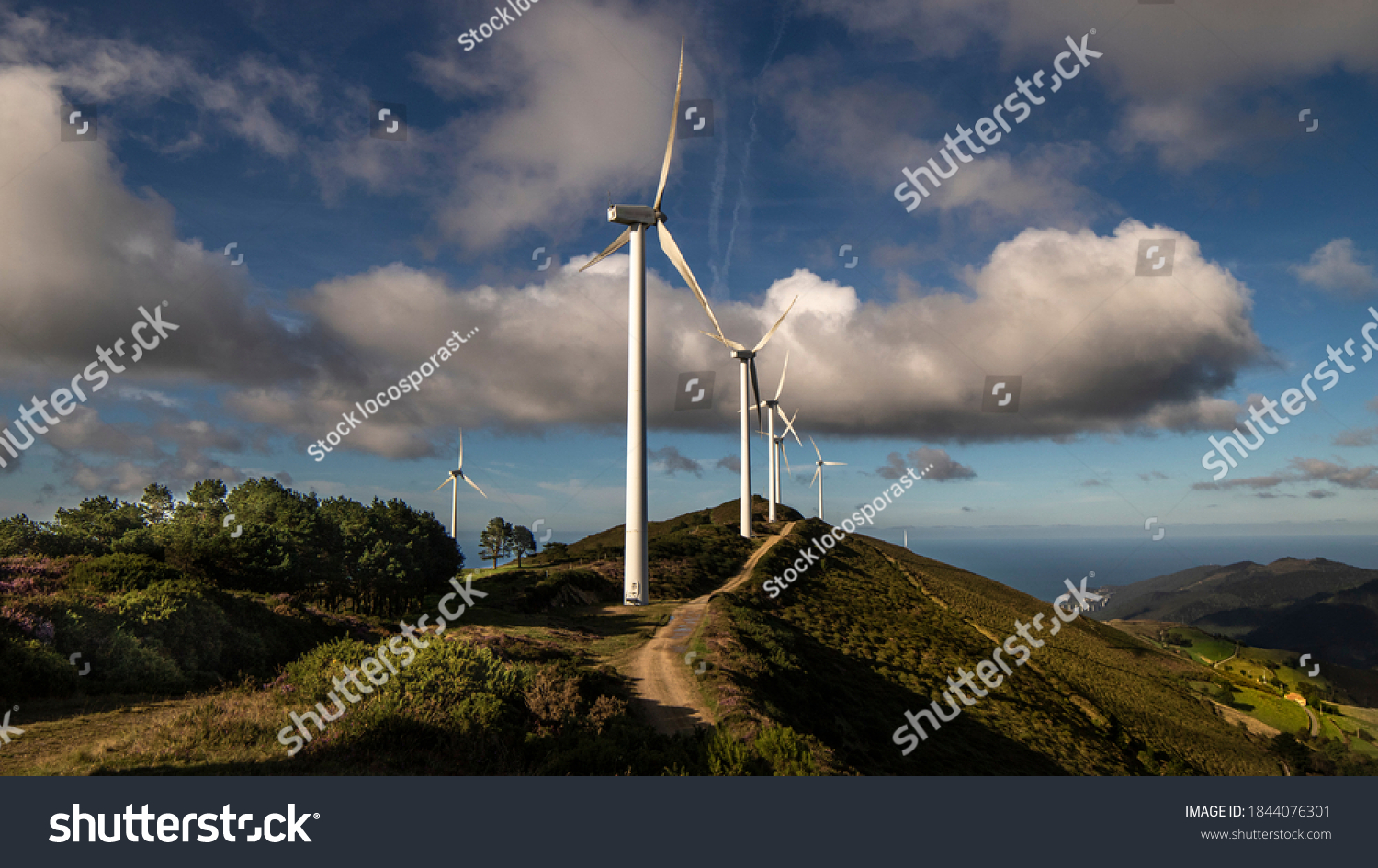 Wind generators  road to energy transition on a hill and a background of clouds
